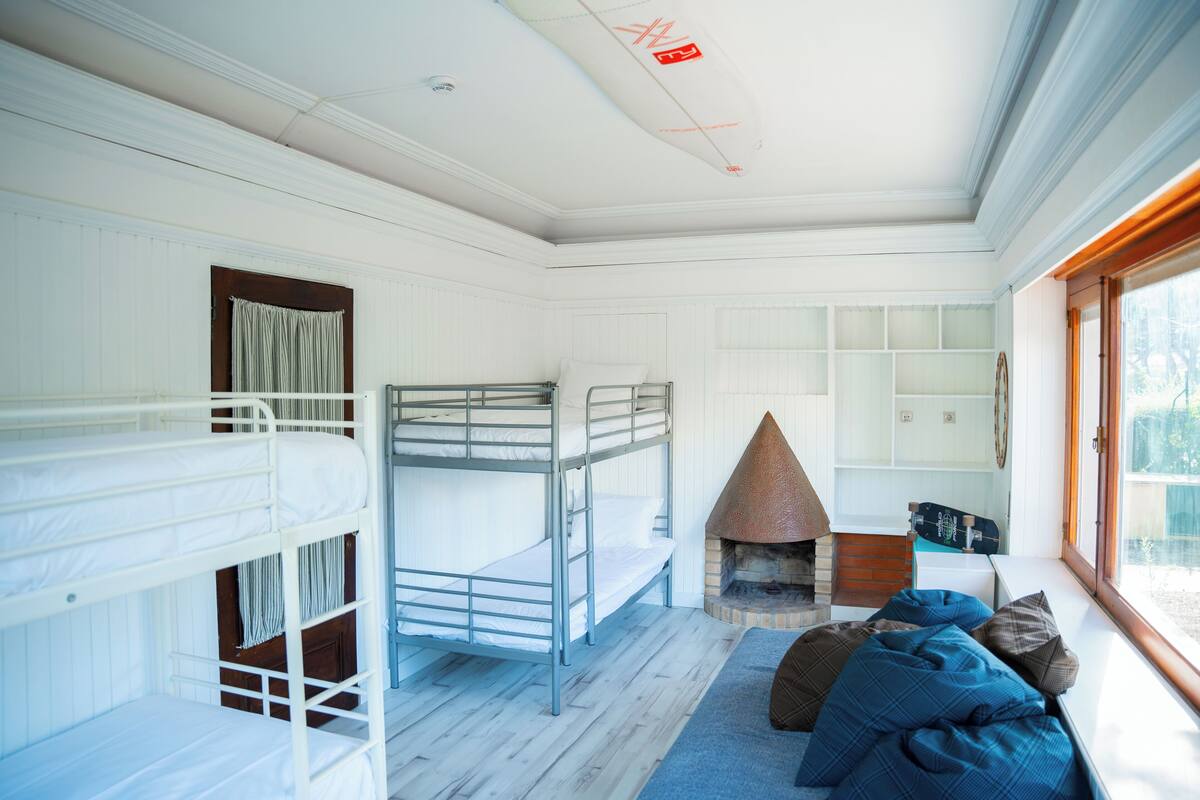 A bunk room with a fireplace, a window with a view, and a skateboard leaning against the wall.