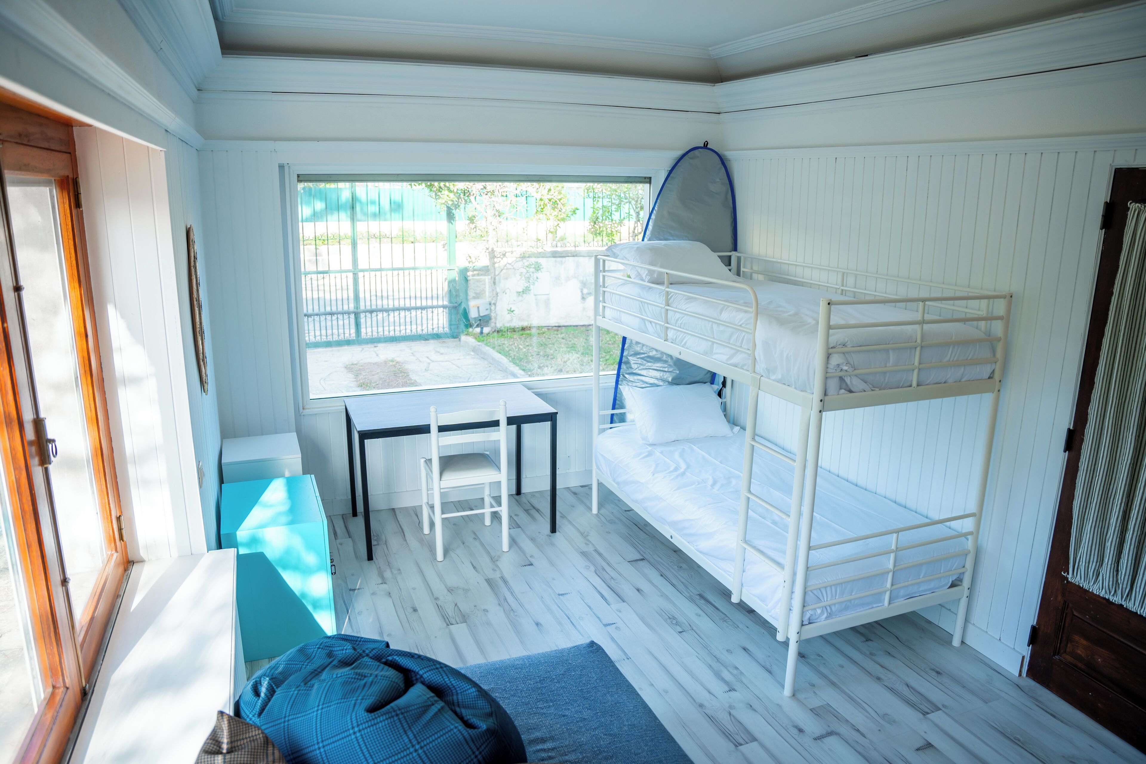 Dormitorio con literas, ventana, mesa y silla.