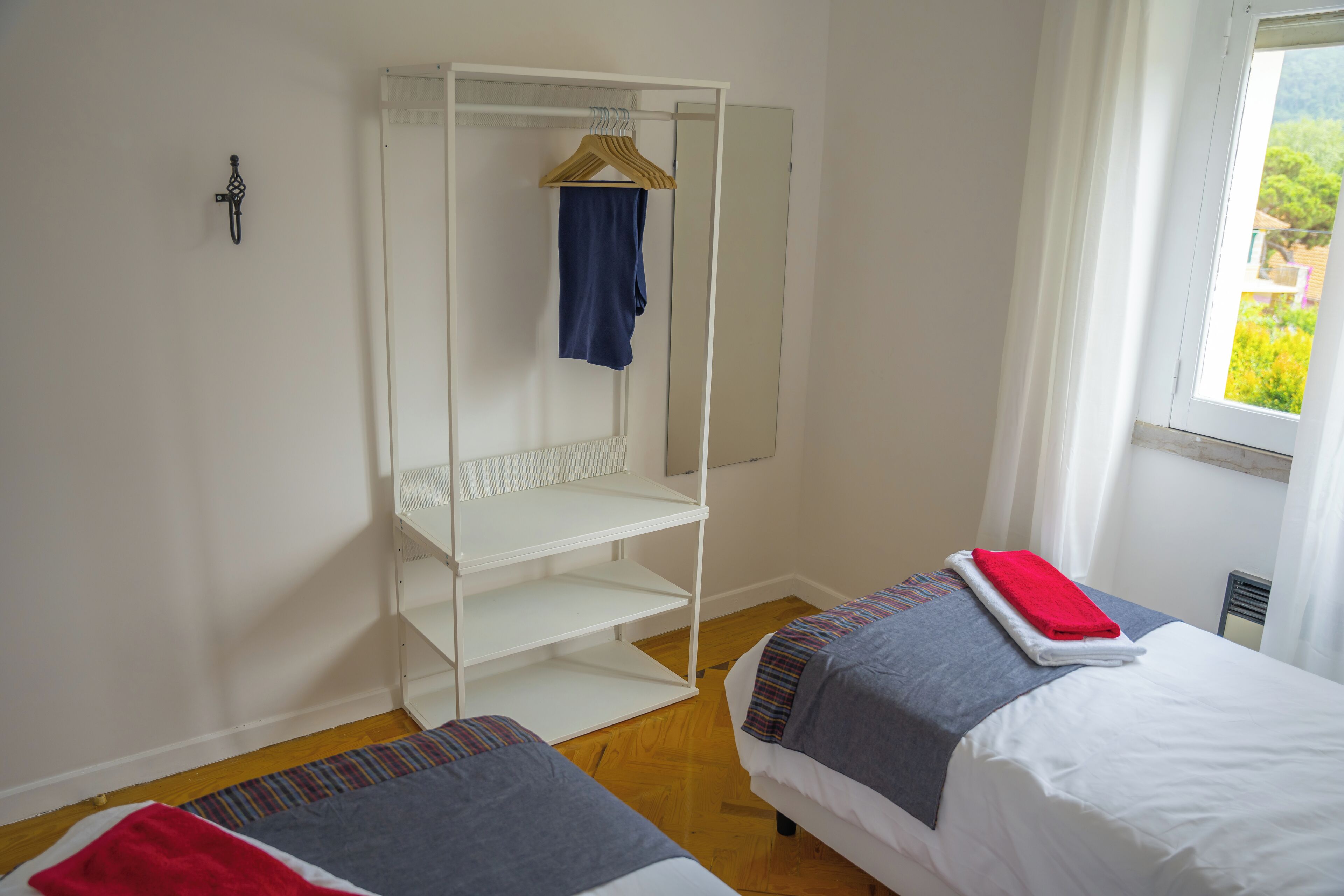 Una habitación con dos camas, un armario y una ventana con vistas.