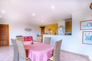 Un coin repas avec des chaises en osier, une nappe rose et une porte en bois.