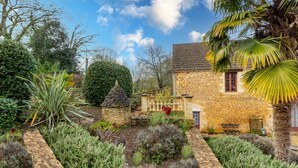 Una casa in pietra con un giardino, un sentiero in pietra e una panchina.