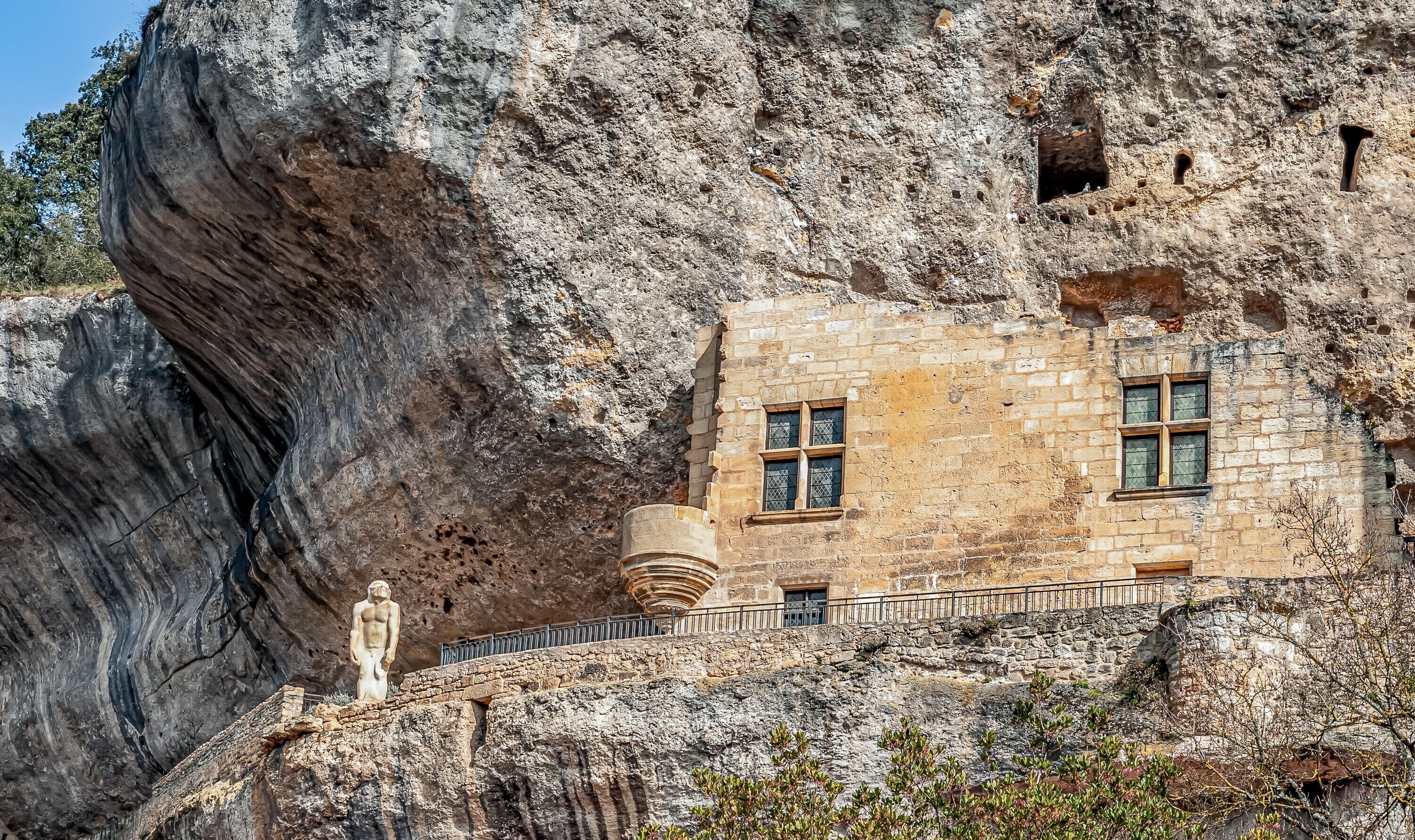 Ein Steinhaus mit einer Statue, einem Fenster und einer Steintreppe.