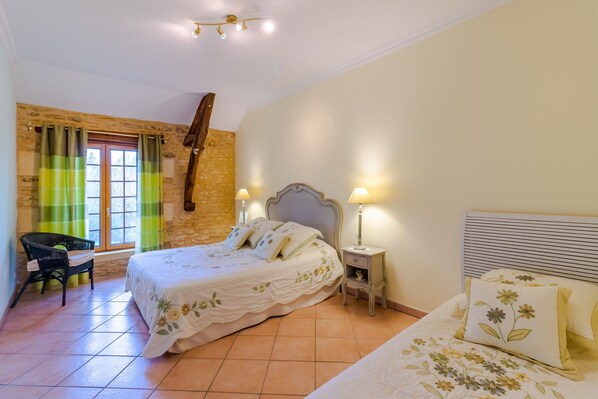 A bedroom with a bed, a chair, a nightstand, and a window with curtains.