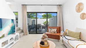 A modern living room with a flat-screen TV, a wooden coffee table, a brown sofa, and a white couch. - Casa Bisani in Cupecoy (Sint Maarten)