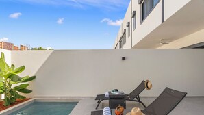 A poolside area with two lounge chairs, a hat, and a crab on a table. - Casa Bisani in Cupecoy (Sint Maarten)