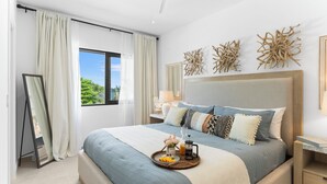A modern bedroom with a large bed, a bedside table with a lamp, a wall-mounted mirror, and a window with curtains. - Casa Bisani in Cupecoy (Sint Maarten)