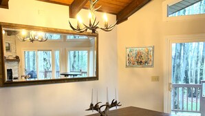 A dining area with a wooden table, benches, a chandelier, a fireplace, a large mirror, and a painting. - Fabulous 3-bedroom chalet in Hidden Valley, PA; walk to the slopes! (Hidden Valley)
