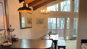 A kitchen with a large island, bar stools, a chandelier, and a view of the backyard through large windows. - Fabulous 3-bedroom chalet in Hidden Valley, PA; walk to the slopes! (Hidden Valley)
