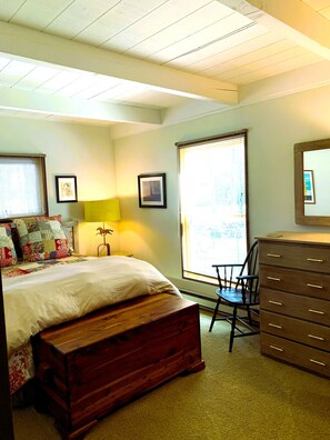 Une chambre à coucher avec un lit, une commode en bois, un bureau et une chaise.