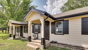 A two-story house with a covered porch, a front door, and a window with shutters. - Hilltop Lookout #2 at Busch Mt- Stunning Views! (Eureka Springs)