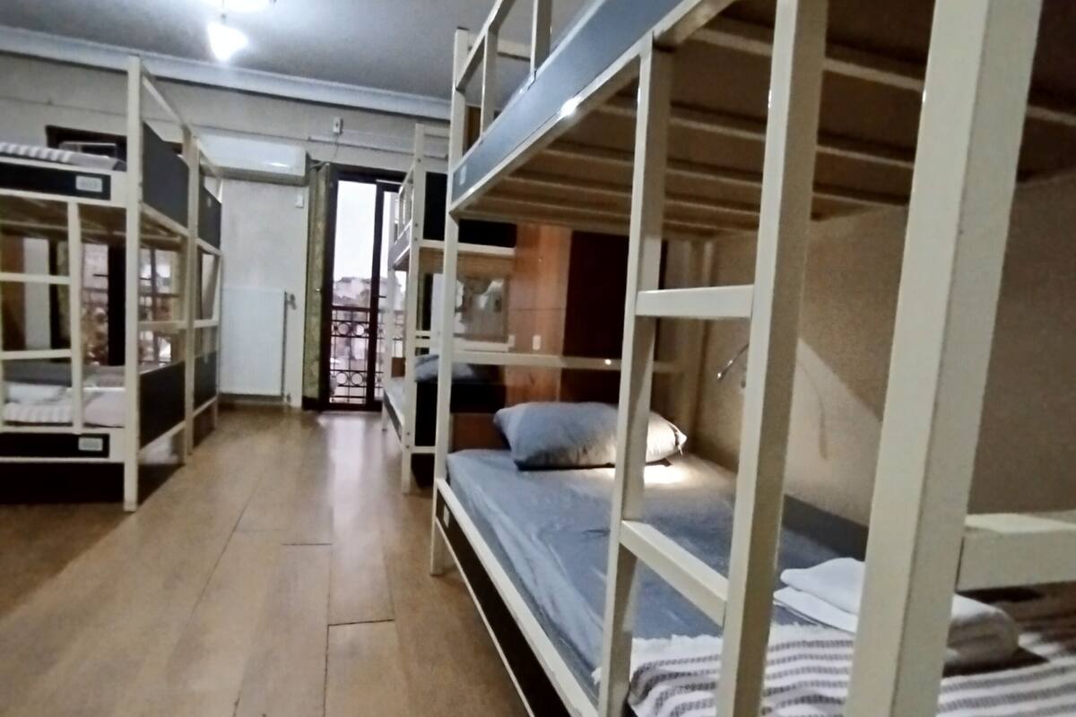 Una stanza del dormitorio con letti a castello, pavimento in legno e una porta che dà su un'altra stanza.