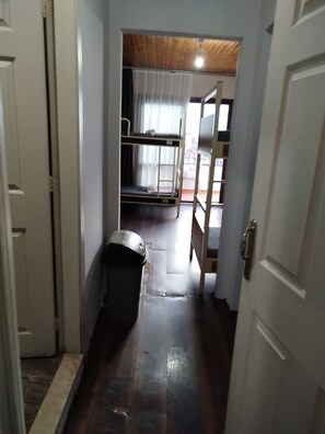 A narrow hallway with a bunk bed, a trash bin, and a door leading to another room. - ivy hostel (Istanbul)