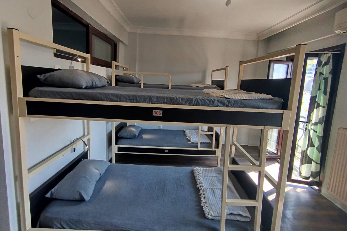Una camera in stile dormitorio con letti a castello, una finestra e una ventola a soffitto.
