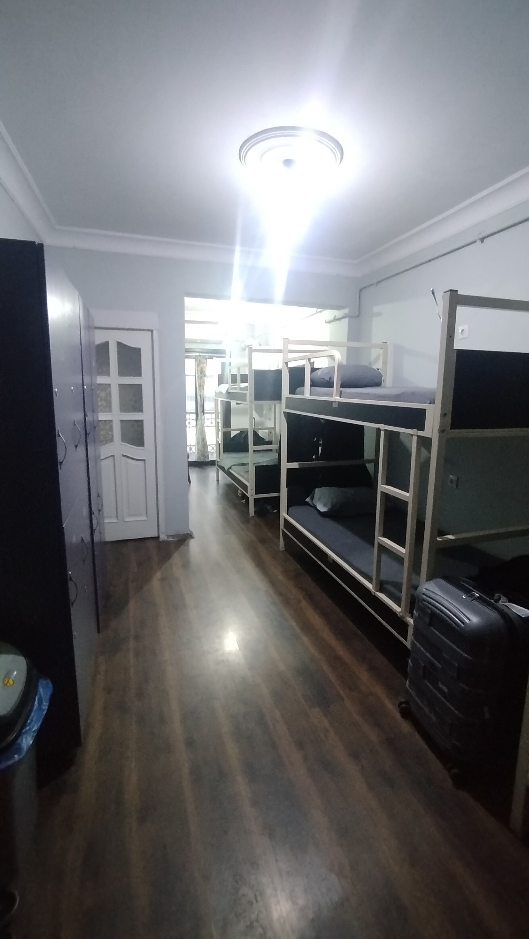 Een kamer met stapelbedden, een koffer en een deur naar een andere kamer.
