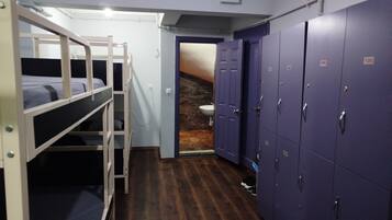 Un dormitorio con literas, un baño con lavabo y una fila de taquillas.