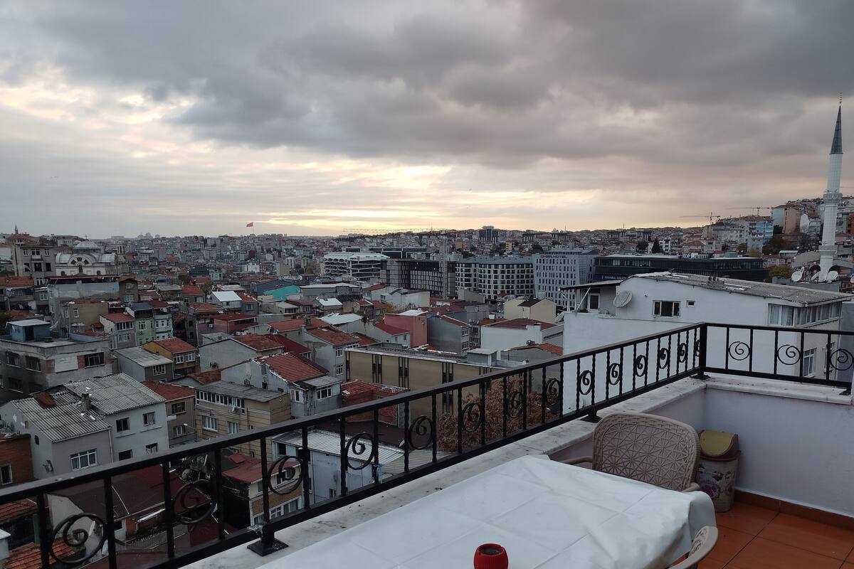 Paesaggio urbano con un balcone dotato di ringhiera in metallo, un tavolo bianco e una sedia.