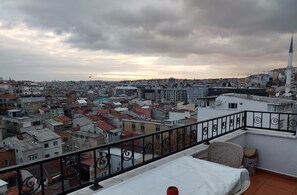 A cityscape with a balcony featuring a metal railing, a white table, and a chair. - ivy hostel (Istanbul)