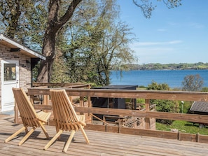 A wooden deck with two chairs overlooking a lake.