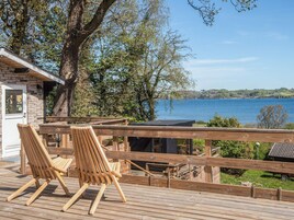A wooden deck with two chairs overlooking a lake.