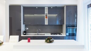Cozinha moderna com armários cinza, bancada branca, fogão a gás e pia.
