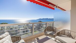 A balcony with wicker furniture and a clear view of the sea and distant mountains. - Bright Apartment With Sea View (Cannes)