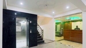 Un vestíbulo con mostrador de recepción, una escalera y un separador de vidrio.