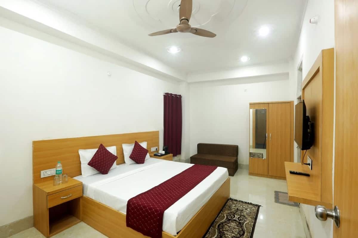 A hotel room with a bed, bedside table, TV, wardrobe, and a ceiling fan.