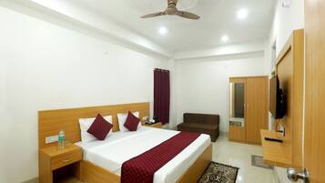 A hotel room with a bed, bedside table, TV, wardrobe, and a ceiling fan.