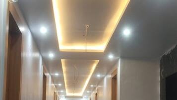 Un couloir doté d’un plancher poli, d’un éclairage encastré et d’un design de plafond moderne.