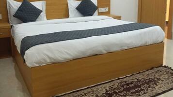 A neatly made bed with a wooden headboard, two pillows, and a dark blanket.