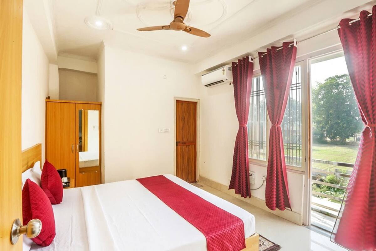 A bedroom with a bed, a ceiling fan, a wardrobe, and a window with curtains.