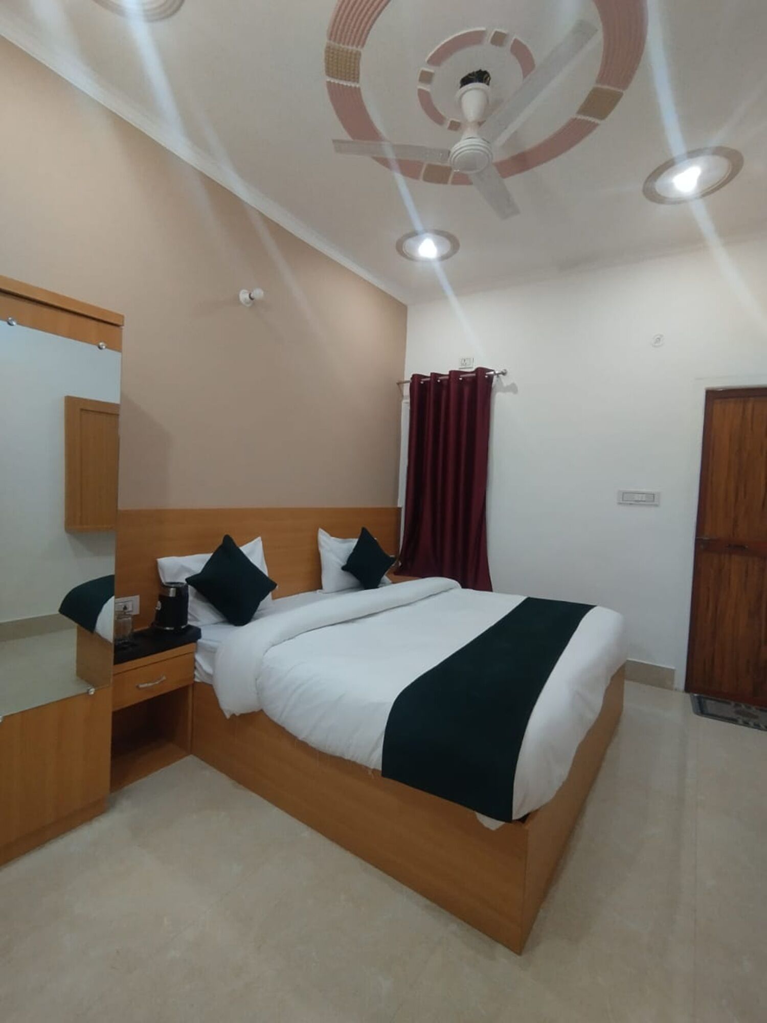 A neatly arranged bedroom with a bed, a bedside table, a mirror, and a ceiling fan.