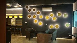 A modern lounge area with a herringbone wood floor, a bar counter, and a seating area with a round table and chairs. - DOMO by Design Union (Lekki)