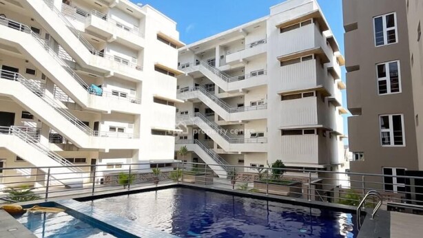 A modern apartment building with a central swimming pool, multiple balconies, and a clear sky. - DOMO by Design Union (Lekki)