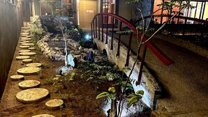 A garden pathway with circular stepping stones, surrounded by plants and a stone wall. - DOMO by Design Union (Lekki)