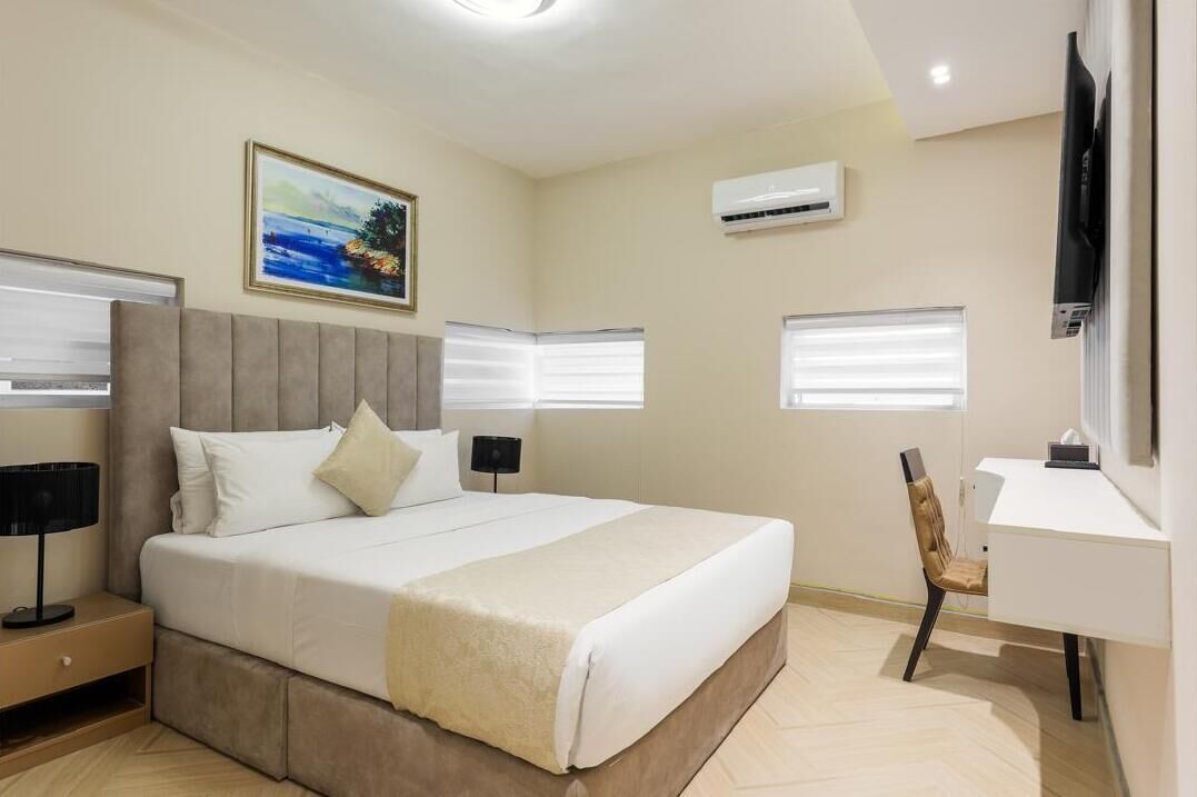 A modern hotel room with a large bed, a desk, and a chair.