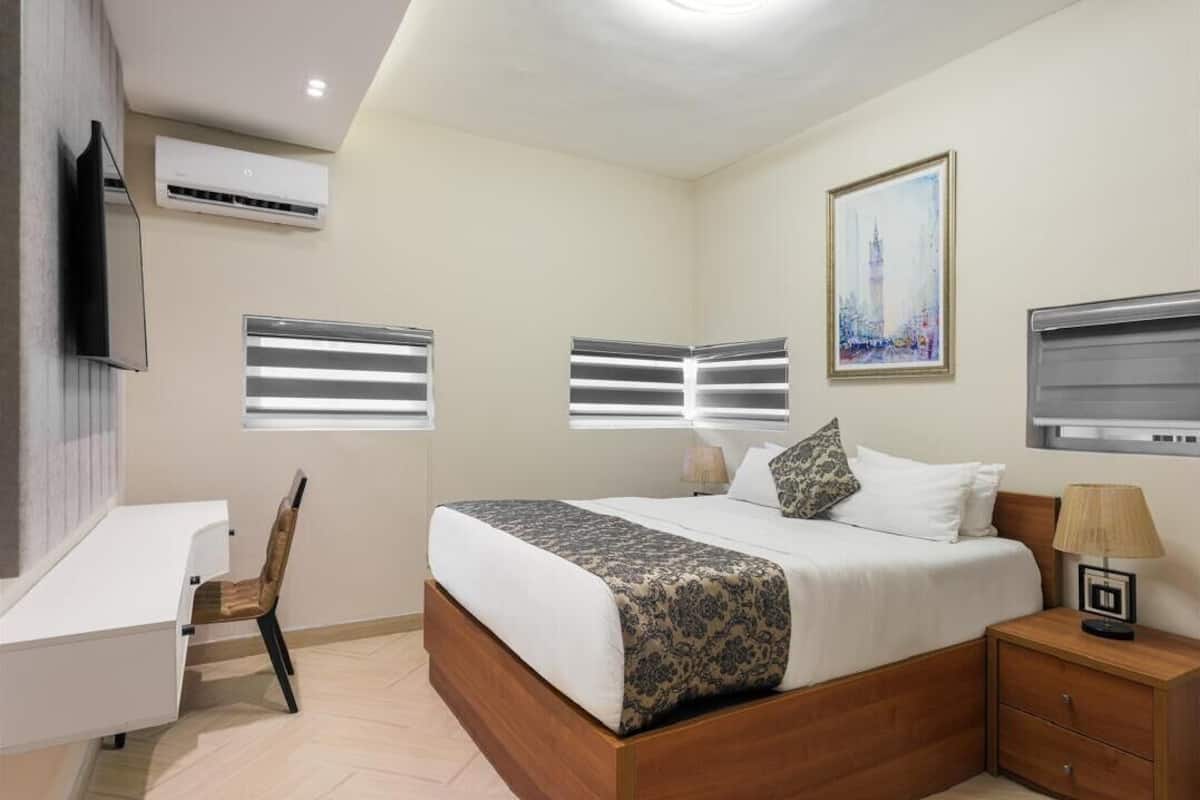 A bedroom with a bed, bedside tables, a desk, and a chair.