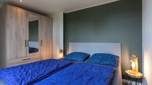 Un dormitori amb un llit, un armari i una petita taula de nit amb una làmpada.