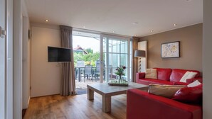 Un saló modern amb un sofà vermell, una taula de centre de fusta i un televisor de pantalla plana muntat a la paret.