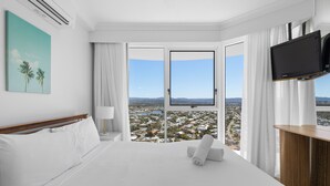 Habitación de hotel con una cama grande, televisión de pantalla plana, escritorio y ventana con vistas a la ciudad.