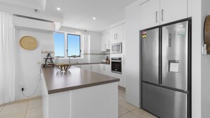 Una cocina moderna con armarios blancos, electrodomésticos de acero inoxidable y una isla central.