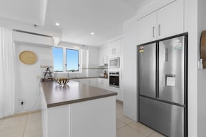 Una cocina moderna con armarios blancos, electrodomésticos de acero inoxidable y una isla central.