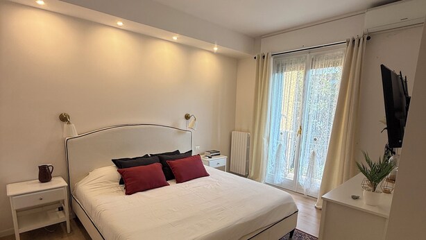 Un dormitorio moderno con una cama grande, mesitas de noche, un radiador y una ventana con cortinas.