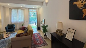 Un moderno salón con sofá, sillón y una mesa de centro. Hay un mapa del mundo en la pared y una lámpara sobre una consola.
