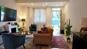 Una sala de estar con un sofá, un sillón y un televisor de pantalla plana montado en la pared.