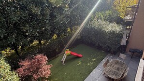 Un patio trasero con un área de juegos, una mesa de madera y una silla.