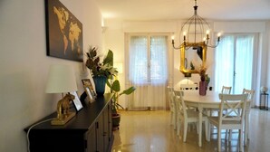 Un comedor con una mesa redonda, sillas blancas, una araña de cristal y un mapa del mundo en la pared.