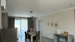 Una cocina moderna con un refrigerador empotrado, un comedor con mesa y sillas, y una pequeña consola decorada con objetos ornamentales.