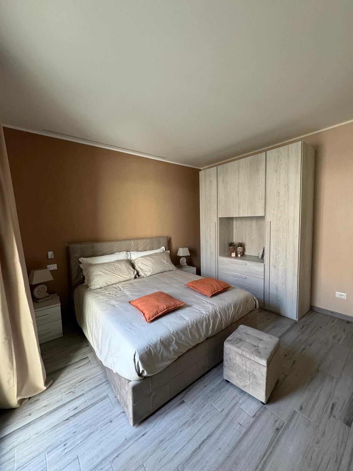 Un dormitorio con cama, mesitas de noche, armario y una pequeña zona de estar.