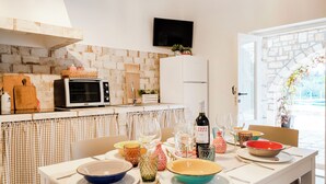 Ein Essbereich mit Tisch für vier Personen, eine Küche mit Mikrowelle und Toaster sowie ein an der Wand montierter Fernseher.